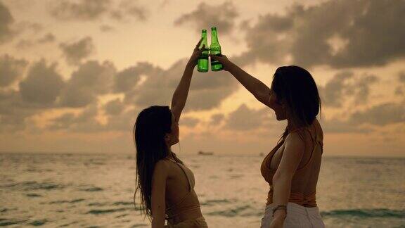 两个美丽的亚洲女人在日落的海滩上跳舞度假自由旅游冒险无忧无虑
