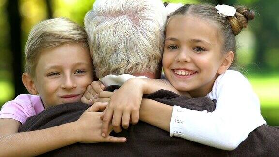 孙子们跑到坐在长凳上的爷爷身边拥抱他亲吻他