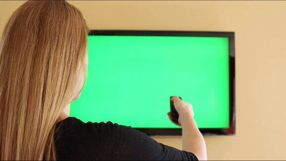 女人在绿屏电视上换频道