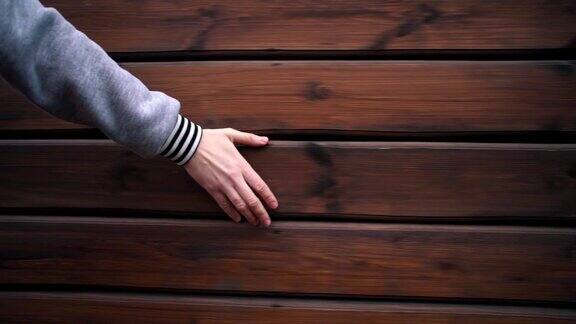 女人的手摸着一堵木墙
