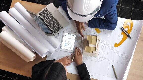 建筑师和客户用蓝图和建筑模型定义设计细节