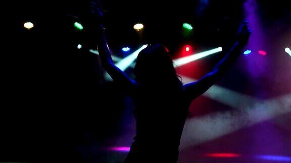 黑暗中一个快乐放松的跳舞女孩的剪影