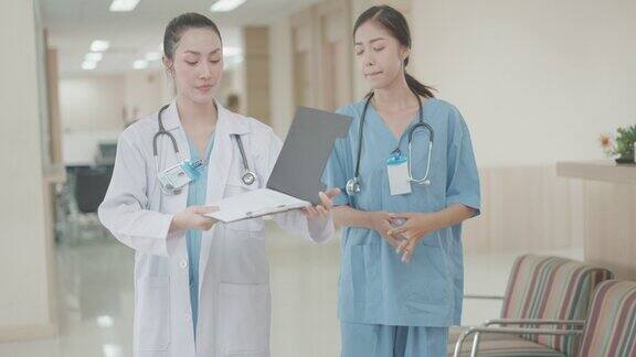 亚洲女医生和护士在走廊上散步讨论诊断和治疗谈论病人的病情和住院的程序专业的医疗团队医务人员医疗保健概念