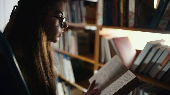 戴眼镜的小女孩坐在图书馆看书