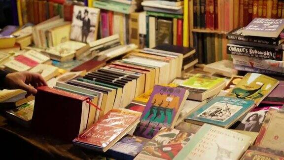 一个年轻人在二手书店里看旧书在波多贝罗路跳蚤市场的一个市场摊位上出售的旧书