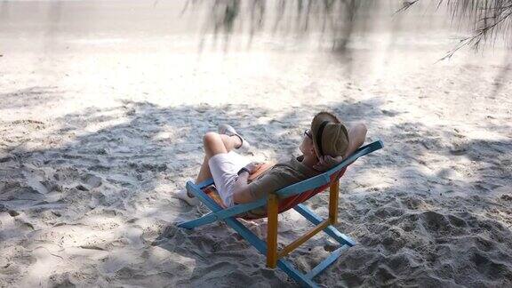 4K亚洲男人在海边的沙滩椅上休息
