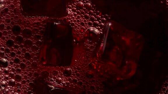 往装满冰块的杯子里倒红色软饮料特写慢镜头饮料和饮料