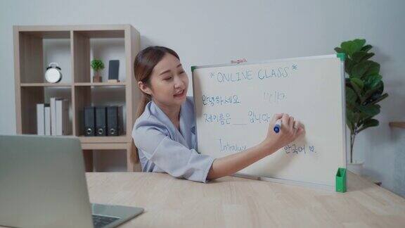 年轻的亚洲女性穿着休闲使用白板教学在公寓在线课堂