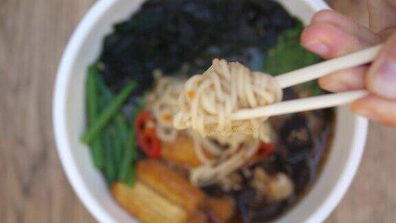 健康的有机亚洲菜肴最上面的镜头是筷子从热的新鲜辣拉面汤中挑出面条
