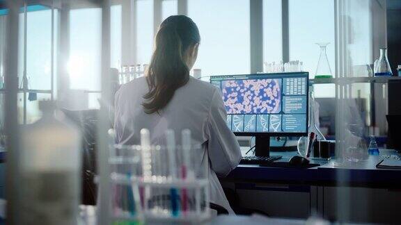 医学实验室由专业生物技术科学家组成的多样化团队开发药物女性生物化学家从事计算机显示基因治疗界面的工作后视图拍摄