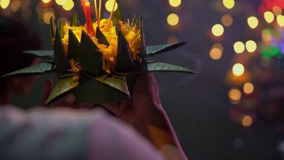 慢动作镜头一个人拿着一个krathong在他的手中燃烧的蜡烛庆祝一个传统的泰国节日-LoyKrathong