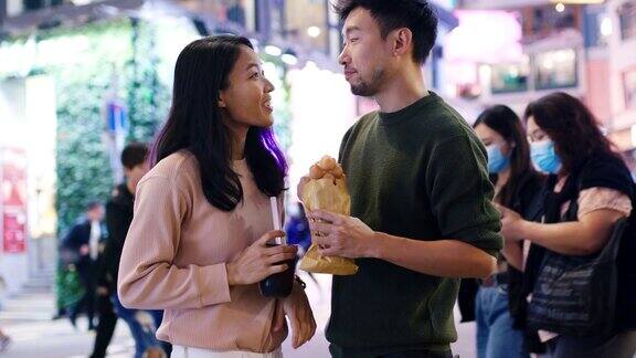 SLOMO手持中景拍摄一对年轻夫妇在香港吃传统街头小吃