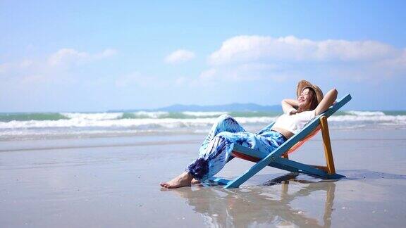 4K美丽的亚洲女人在海边的沙滩椅上休息