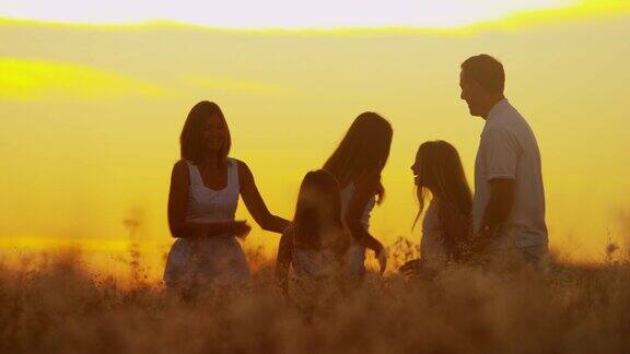 高加索家庭在日落的剪影一起在户外玩