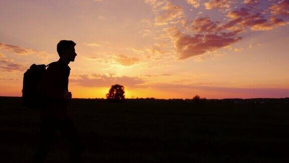 一个少年背着背包走向田野或乡村的夕阳剪影视频侧视图概念新的研究向未知的方向前进离开家