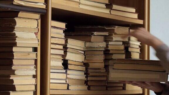 书架上有旧书一位女士正在图书馆的书架上找书人类选择书籍白种人用手触摸书架上的书阅读与教育