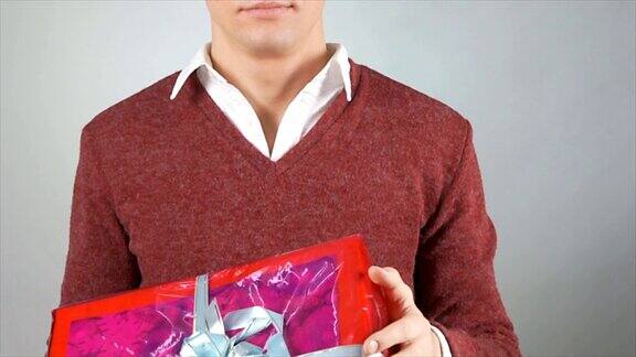 一个年轻人和一份礼物一个有吸引力的男人拿着一个盒子