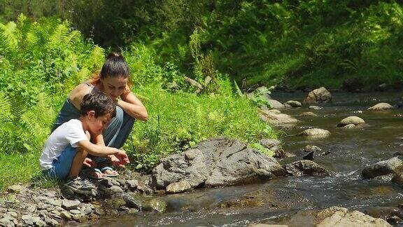 母亲和她的儿子坐在小溪边
