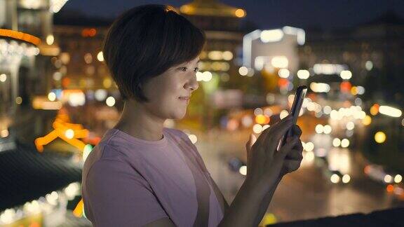 晚上在城市街道上用智能手机的女人