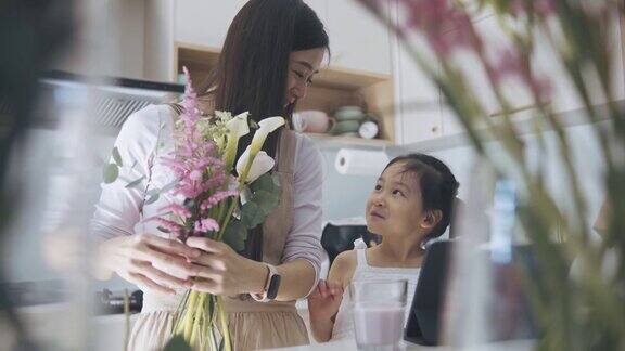 亚洲女性花商与她的女儿谈话在厨房使用数字平板电脑指导工作