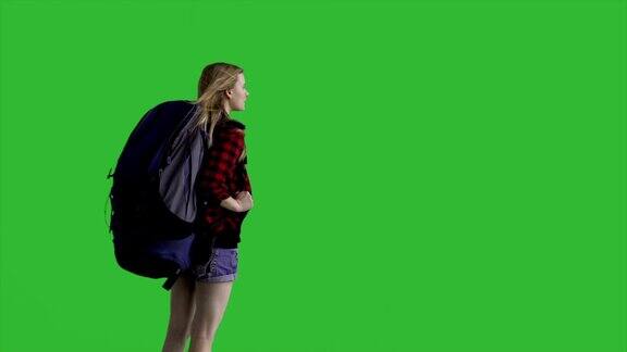 年轻迷人的女性徒步旅行者与一个背包看向远方-绿色屏幕