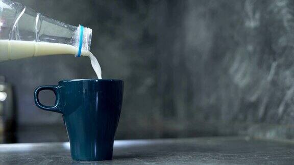 将咖啡倒入深蓝色的杯子中然后倒入牛奶用勺子搅拌
