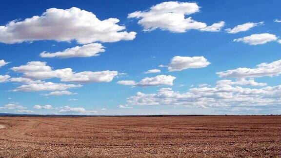 时间流逝的观点飞行白云在天空在棕色的田野