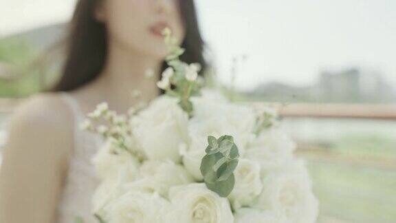 一个美丽年轻的亚洲新娘手里拿着白色的鲜花对着镜头微笑中国新娘