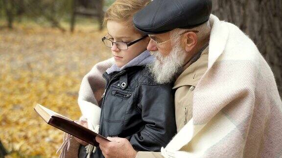 爷爷和孙子在秋天的公园里看书