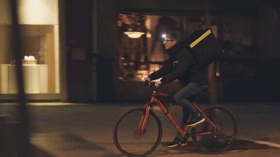 一个背着背包的男人晚上骑自行车送食物