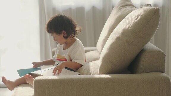 亚洲小男孩在沙发上看书