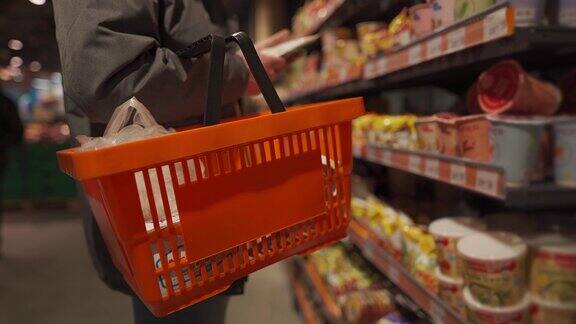 一名男子推着橙色购物车在超市挑选商品选购商品时抱着购物车的男性关注商店中买家手中的一篮子商品选择产品