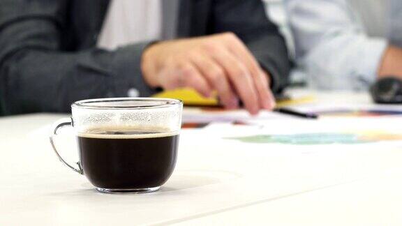 近距离的一杯咖啡在桌子上的商人工作的背景