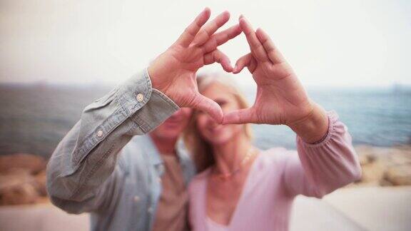 一对浪漫的老夫妇正在用手做一个心形