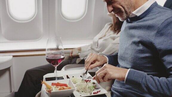成熟的商人在私人飞机上吃午餐