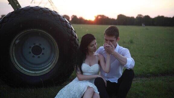 相爱的情侣坐在农用喷雾器附近的水滴下拥抱