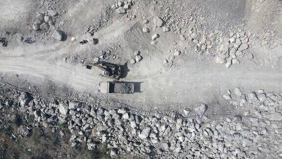 一辆自卸卡车在露天矿山的土路上运输岩石的鸟瞰图