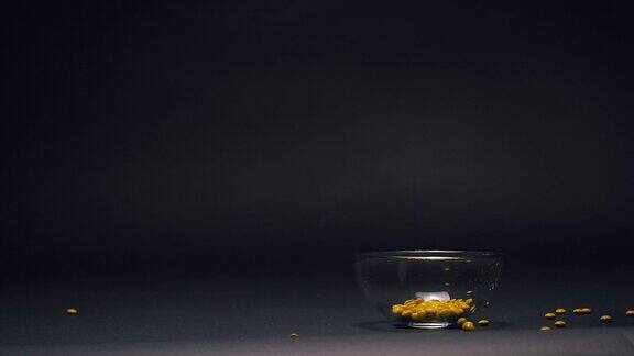 黄色糖果在玻璃碗中缓慢下落复制空间在黑色黑板纹理背景上
