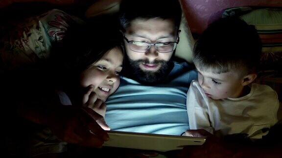父亲带着孩子们在睡觉前玩平板电脑