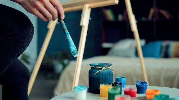 艺术家把画笔放在一个盛有水的罐子里然后把它浸在颜料里艺术家的手用画笔在纸上抓住线条自底向上的视图