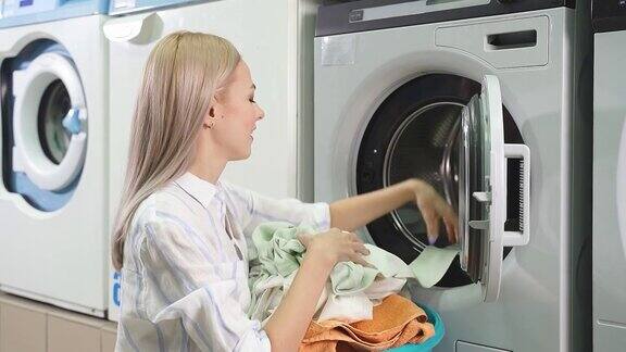 洗衣机洗脏衣服女人把干净的衣服从洗衣机里拿出来公共自助洗衣
