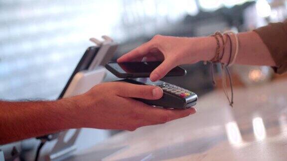 女性用智能手机在餐厅使用非接触式支付技术