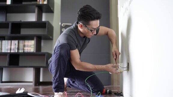 亚洲华人男性电工连接插座到电线将电线安装到插头上