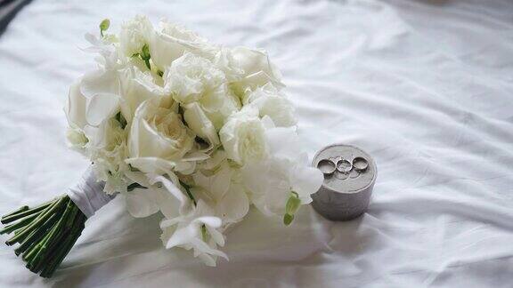 在一张白色的床单上有一束鲜花和两枚结婚戒指俯视图大图