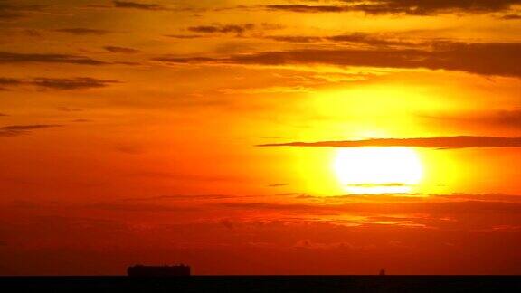 夕阳橘黄色的天空红色的云在海上移动剪影货船和渔船的时间流逝