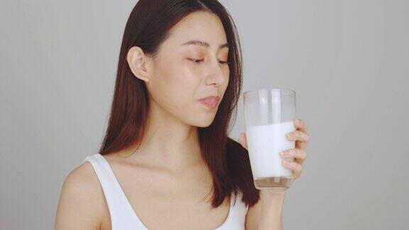 年轻和快乐的亚洲女人喝新鲜的牛奶在白色的背景清洁平衡的健康食品理念健康饮食与健身理念有机食品医疗保健理念