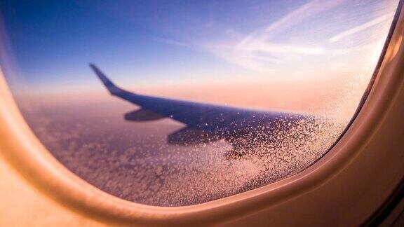 透过飞机窗户观看橙色的云和天空