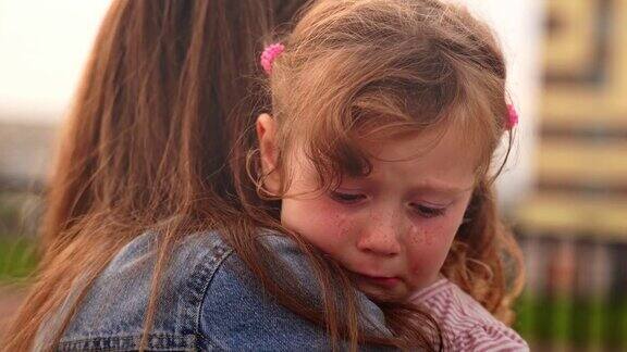 年轻的母亲安抚她伤心哭泣的小女孩