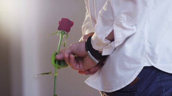 手里拿着一朵红玫瑰的男人