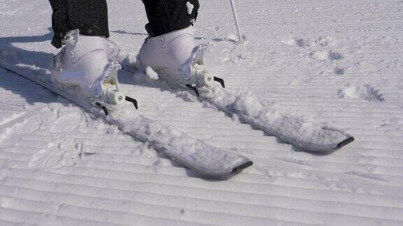 在一个阳光明媚的日子里滑雪者踩进滑雪绑定与他的滑雪靴